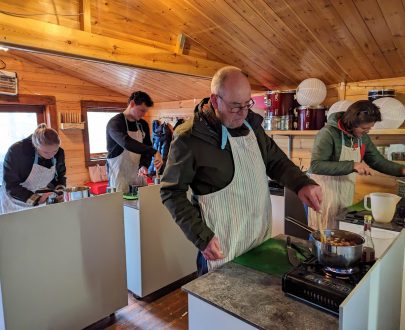 Picture of people at cooking stations in the log cabin making chilli sauces and jams.