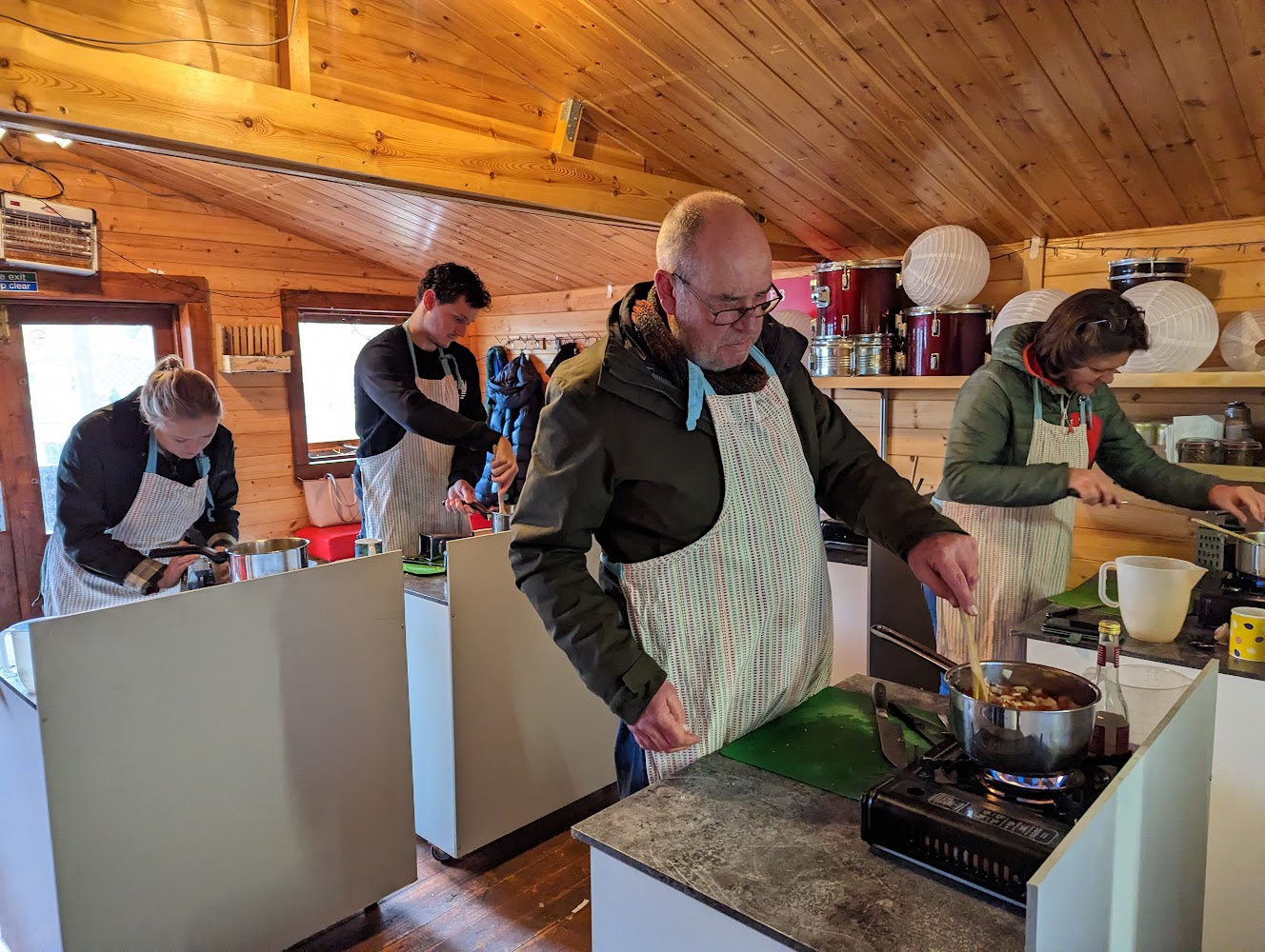 Picture of people at cooking stations in the log cabin making chilli sauces and jams.